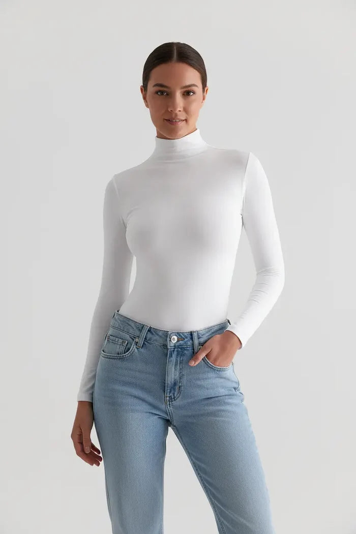 Slim fit turtleneck top for women styled with light blue jeans on white background