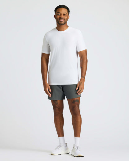 Man wearing White Active Crew Neck Tee, dark gray shorts, and white sneakers.