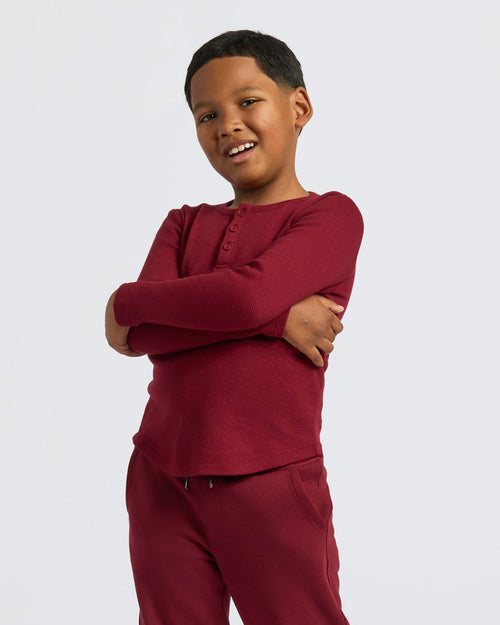 Boy wearing Boys' Waffle Long Sleeve Henley, burgundy, smiling confidently.