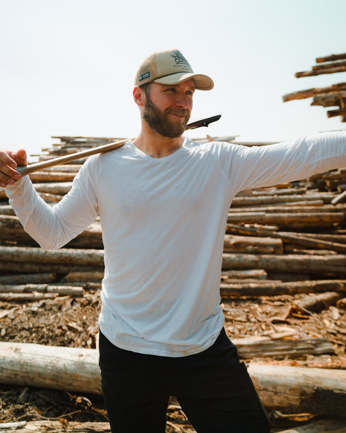 Man holding a axe with stacked logs in the background