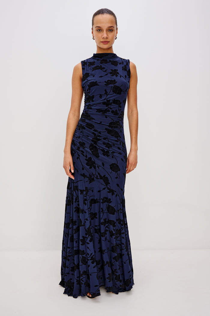 Cosmos Maxi-Length Dress with a Cowl Neck, Sleeveless, Form Fitting with a Ruched Side Seam Detail and an A-line Hem in Navy Tossed Roses Colorway. Full Body Front View Shown on Model.