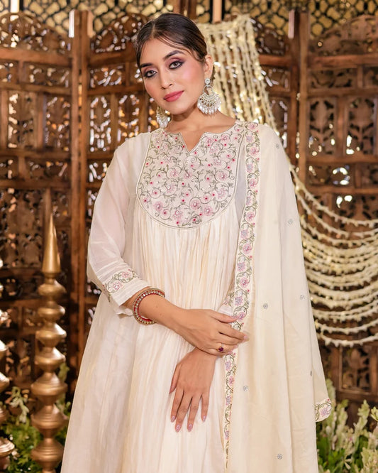 Woman in a traditional outfit with intricate embroidery against a decorative background