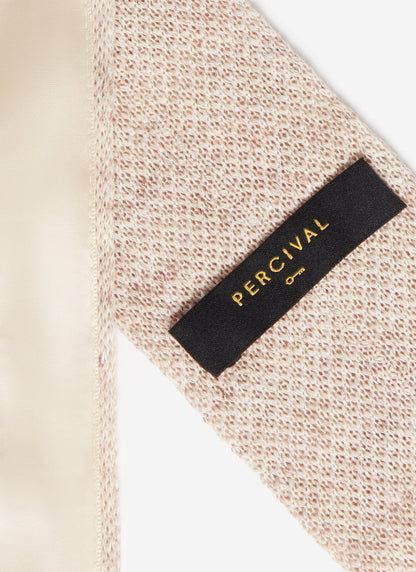 A close-up of the textured oat marl linen and black brand label on the back of the Percival Linen Tie.