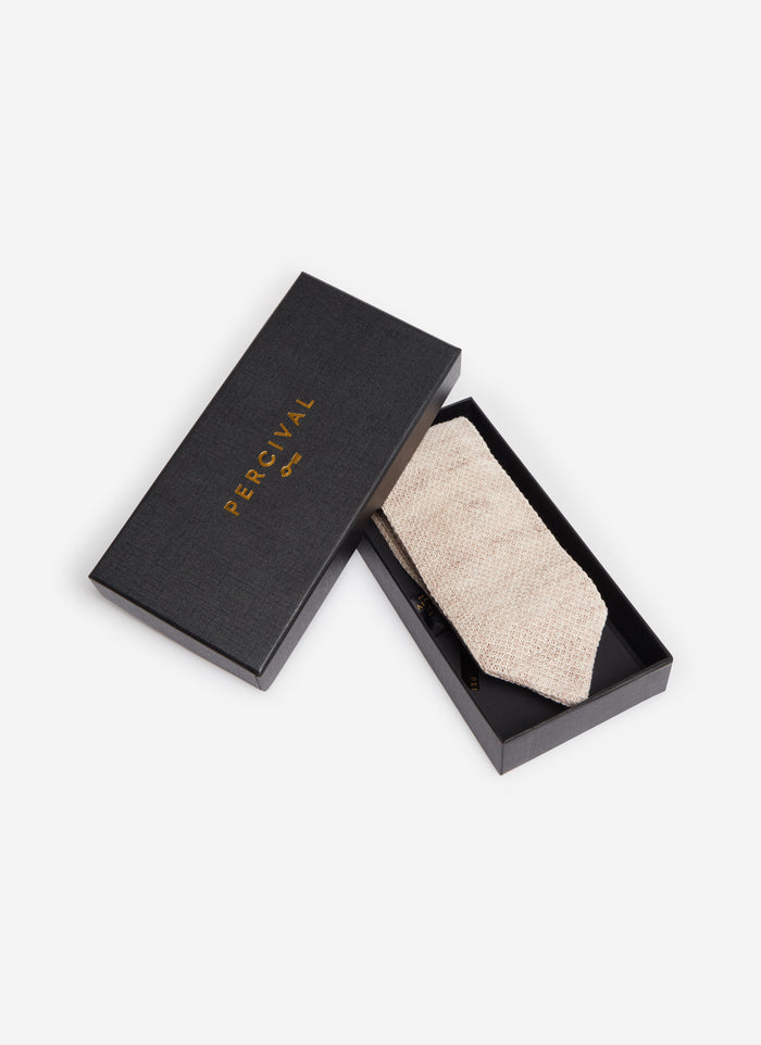 The Percival Linen Tie in Oat Marl, folded and presented in its black branded box against a white background.
