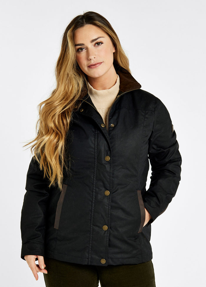 A close up of a female model's hand in the pocket of a Dubarry Mountrath Waxed jacket, black jacket, brown leather detail on edge of pocket