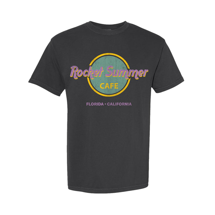 A black Comfort Colors T-shirt by The Rocket Summer, garment-dyed with a retro circular café logo in purple and yellow, featuring “Florida • California” beneath.