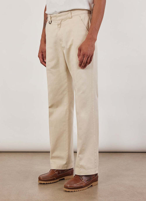 A model seen from the side wears the Percival Stay Press Trousers in ecru cotton twill with brown boat shoes.
