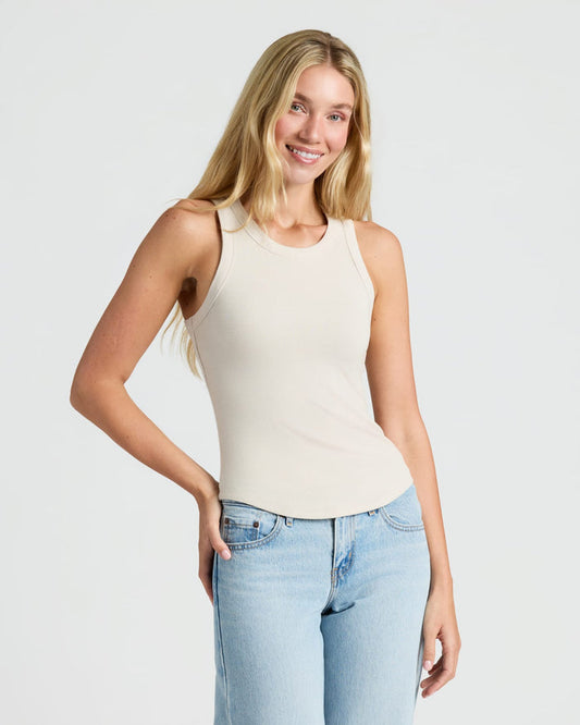 Woman in cream Womens Ribbed High Neck Tank 3-Pack, smiling confidently. MODEL_INFO: Cora is 5'10", wearing a size S