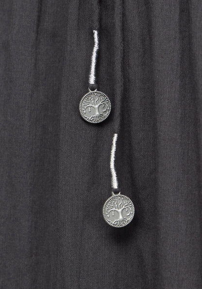 Close up detail of two silver pendants on a grey midi dress